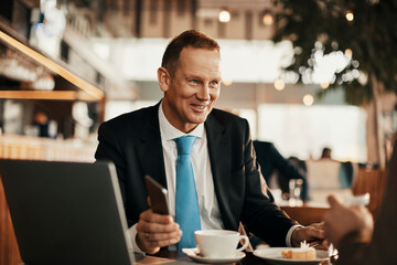 Two businessman having coffee and a meeting in a cafe bar decorated for christmas and the new years holidays