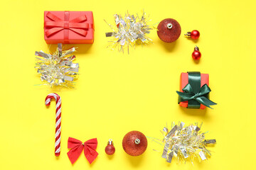 Frame made of Christmas decorations and gifts on yellow background