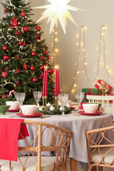 Festive table setting with burning candles and Christmas decorations in dining room