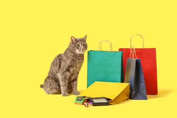 Cute cat and shopping bags with grooming brushes on yellow background