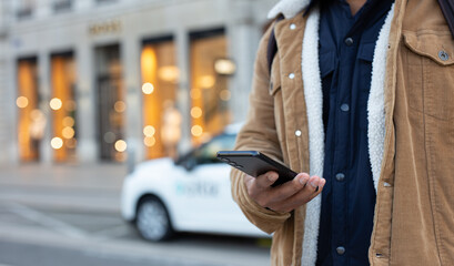 Tourist using smartphone app for renting electric car in the city center