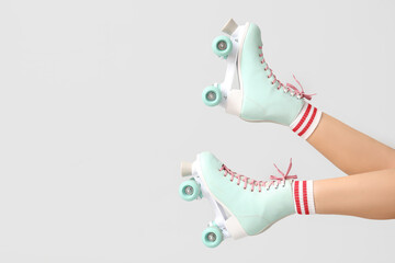 Legs of young woman in roller skates on grey background