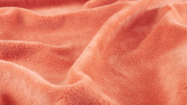 Soft folds of natural velvet peach shades of pink. Textile background on the theme design, fashion, tailoring and accessories. Textured fabric on a rotating display case. Close-up view.