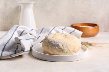Plate with fresh raw dough and wheat on white background