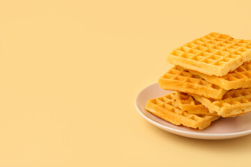 Delicious Belgian waffles in plate on yellow background