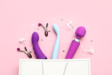 Shopping bag with different vibrators and nipple clamps on pink background