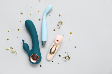 Different vibrators and confetti on grey background