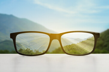 Glasses against beautiful landscape. View through lenses more clear. Vision correction