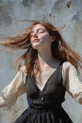 Naklejka premium A woman in a black dress blows her hair while outside, possibly on a windy day