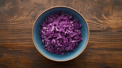 A bowl of chopped red cabbage on a wooden table.