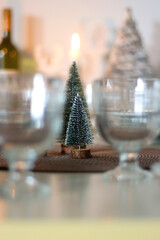 Table set for Christmas meal with plates, glasses, holiday decorations, lit candles and wine. Selective focus.