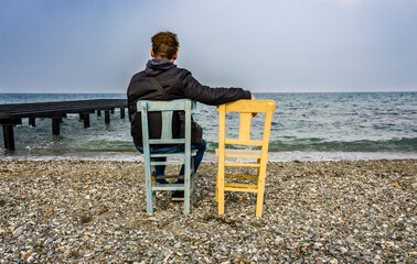 Man Sitting on the Beach with Empty Chair 