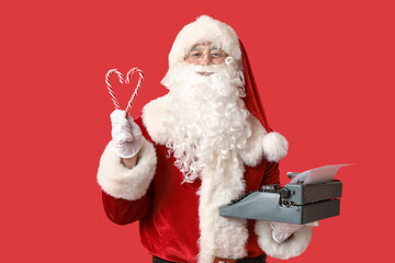 Santa Claus with vintage typewriter and candy canes on red background
