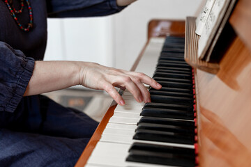 Close-up of a hand playing the piano keys. A musician or a student studying the part