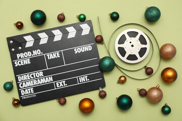 Composition with movie clapper, film reel and Christmas decorations on green background. Top view