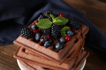 Plate of sweet chocolate Belgian waffles with fresh berries and mint on wooden background