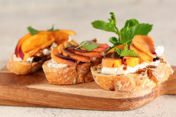 Wooden board of peach bruschetta with ricotta and mint on white background