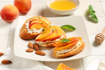 Plate of peach bruschetta with ricotta, basil and almond nuts on white tile background, closeup