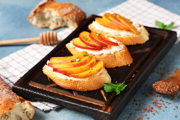 Wooden board of peach bruschetta with ricotta, flax seeds and mint on blue background