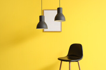 Chair with hanging lamp and frame on yellow wall