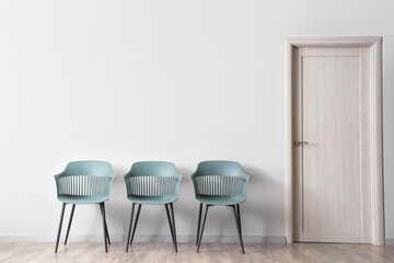 Modern chairs near white wall in room