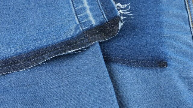 Soft folds of bright blue denim of a muted shade fabric rotate on the showcase. Textile background on the theme of reuse, recycling clothing and textile.