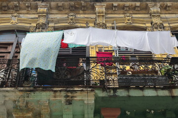 Laundry hung to dry from a clothesline on the balcony with wrought-iron railing of an Eclectic house showing badly maintained facade. Havana-Cuba-817 © rweisswald
