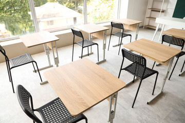 Empty chairs with desks in light classroom