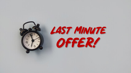 Conceptual black alarm clock with text LAST MINUTE OFFER on grey background