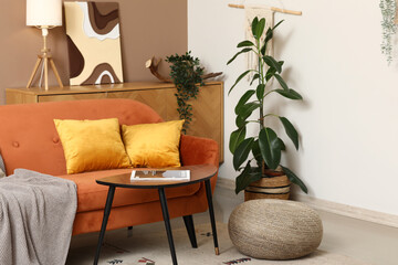 Interior of stylish room with orange sofa, coffee table and houseplant