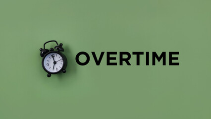 Conceptual black alarm clock with text OVERTIME ongreen background
