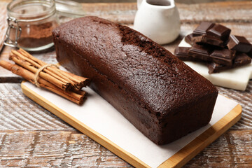 Tasty chocolate sponge cake and ingredients on wooden table, closeup