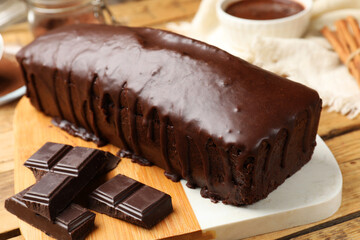 Tasty sponge cake and pieces of chocolate on wooden table, closeup