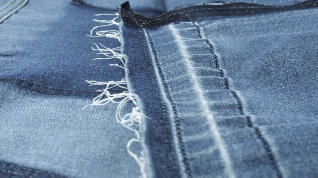 Expressive texture of clothing details after ripping made of dark blue denim of a muted shade rotate on the display case. Texture and quality of cotton fabric. 