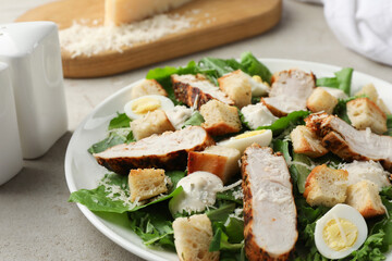 Tasty Caesar salad with chicken on light grey table, closeup