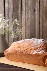 Tasty sponge cake with powdered sugar on wooden table, closeup