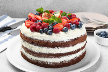 Delicious chocolate sponge cake with berries served on light table, closeup