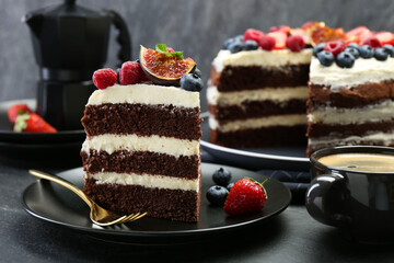 Piece of delicious chocolate sponge cake with berries and coffee on black table, closeup