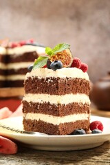 Piece of delicious chocolate sponge cake with berries on wooden table, closeup