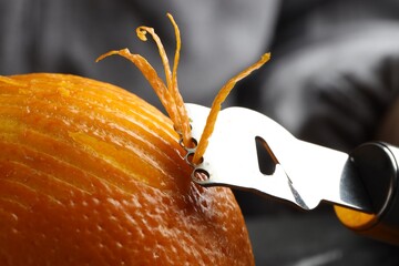 Zesting fresh orange at table, closeup view