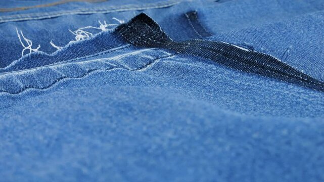 Expressive texture of clothing details after ripping made of bright blue denim rotate on the display case. Textile background on the theme of reuse, recycling clothing and textile.