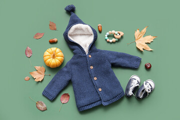 Composition with stylish baby clothes, accessories, pumpkin and fallen leaves on green background