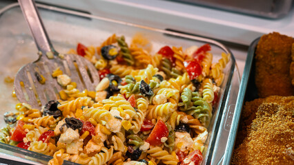 Delicious salad of pasta, olives, tomato with pesto sauce on display at a grocery supermarket