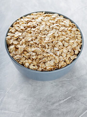 Raw Oat Flakes in Ceramic Bowl on Grey Concrete Background, Healthy Breakfast Ingredient, Top View, Copy Space