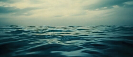 Obraz premium A serene view of calm ocean water under a cloudy sky, evoking tranquility and reflection.