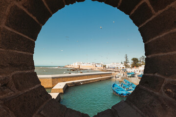 Historical port of Essaouira, Morocco with blue fishing boats docked beside famous ancient fortress...