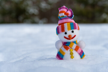 Snowman in christmas clothes stands on white snow in winter forest. Knitted bauble. Christmas and new year holidays decoration. Template for design christmas bauble. Symbol xmas of winter season.