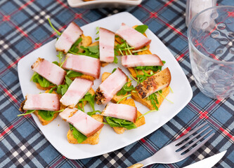 Toast with bacon and arugula served for breakfast on platter