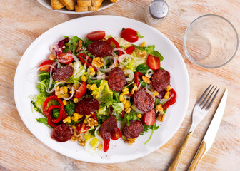 Appetizing salad of fresh vegetables with chorizo, corn and peppers served on platter