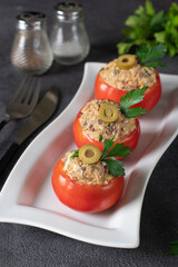Tomatoes stuffed with tuna and olives on white plate